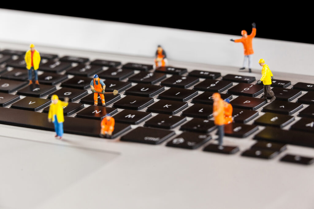 Miniatur-Bauarbeiter sind auf einer LapTop-Tastatur positioniert