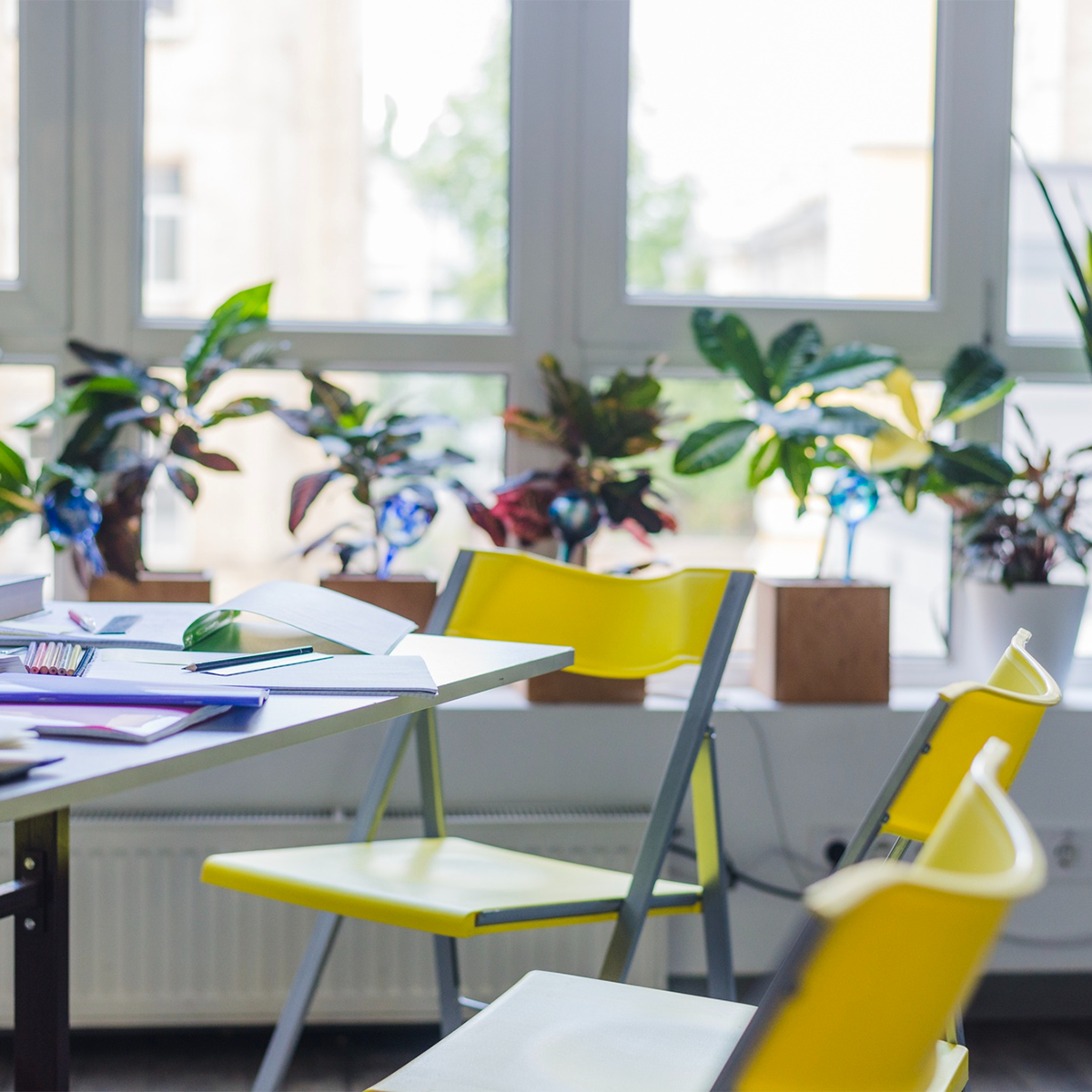 Heller Seminarraum mit Arbeitsunterlagen, gelben Stühlen und Fensterfront